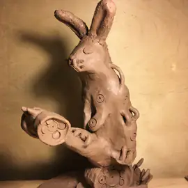 Brown sculpture of a rabbit-like creature with long ears and circular surface patterns, three-quarter view